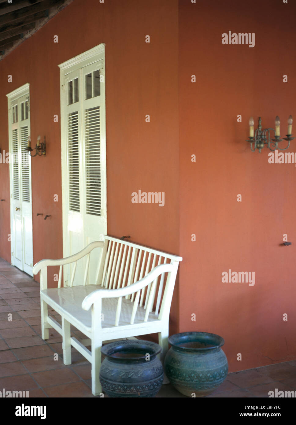 Dipinto di bianco panca sulla veranda di color terracotta casa nel West Indies Foto Stock