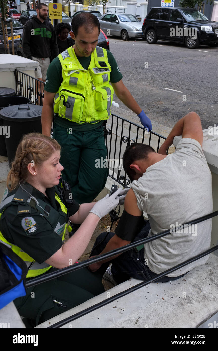 Un reveler al carnevale di Notting Hill riceve attenzione medica da Londra un servizio di ambulanza equipaggio. Foto Stock