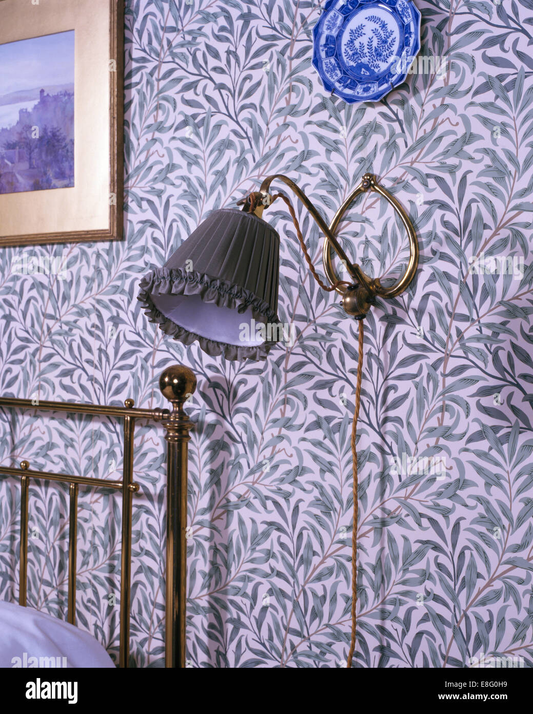 Close-up di lampada a parete con William Morris carta da parati in stile vittoriano camera da letto Foto Stock