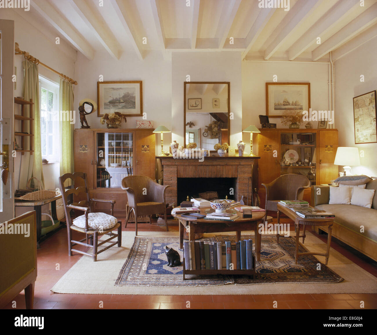 Lloyd Loom sedie e divani confortevoli nel paese francese soggiorno con dipinti di bianco travi a soffitto Foto Stock