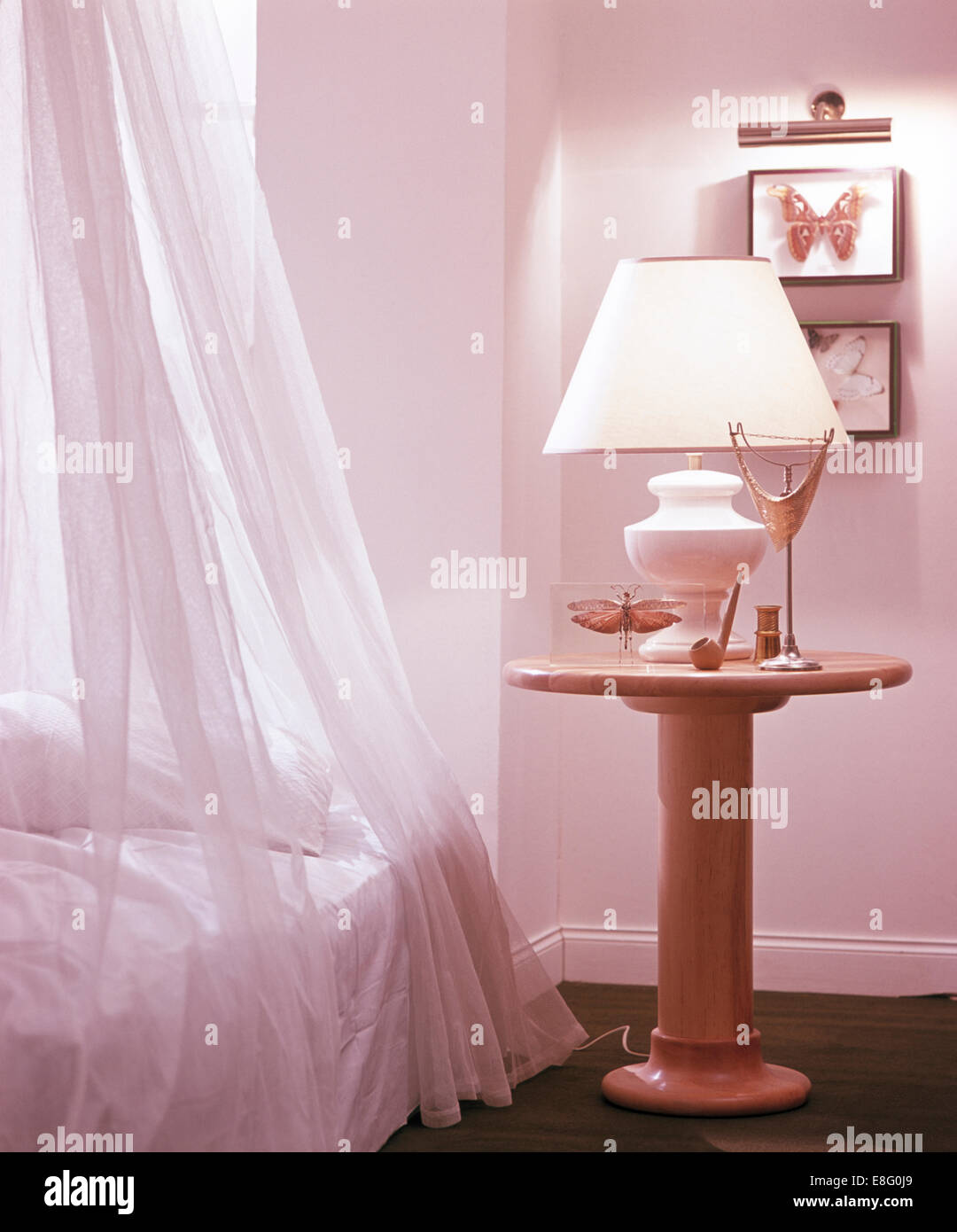 La lampada bianca sul piedistallo tavolo accanto a letto con voile bianco tende in camera da letto degli anni ottanta Foto Stock