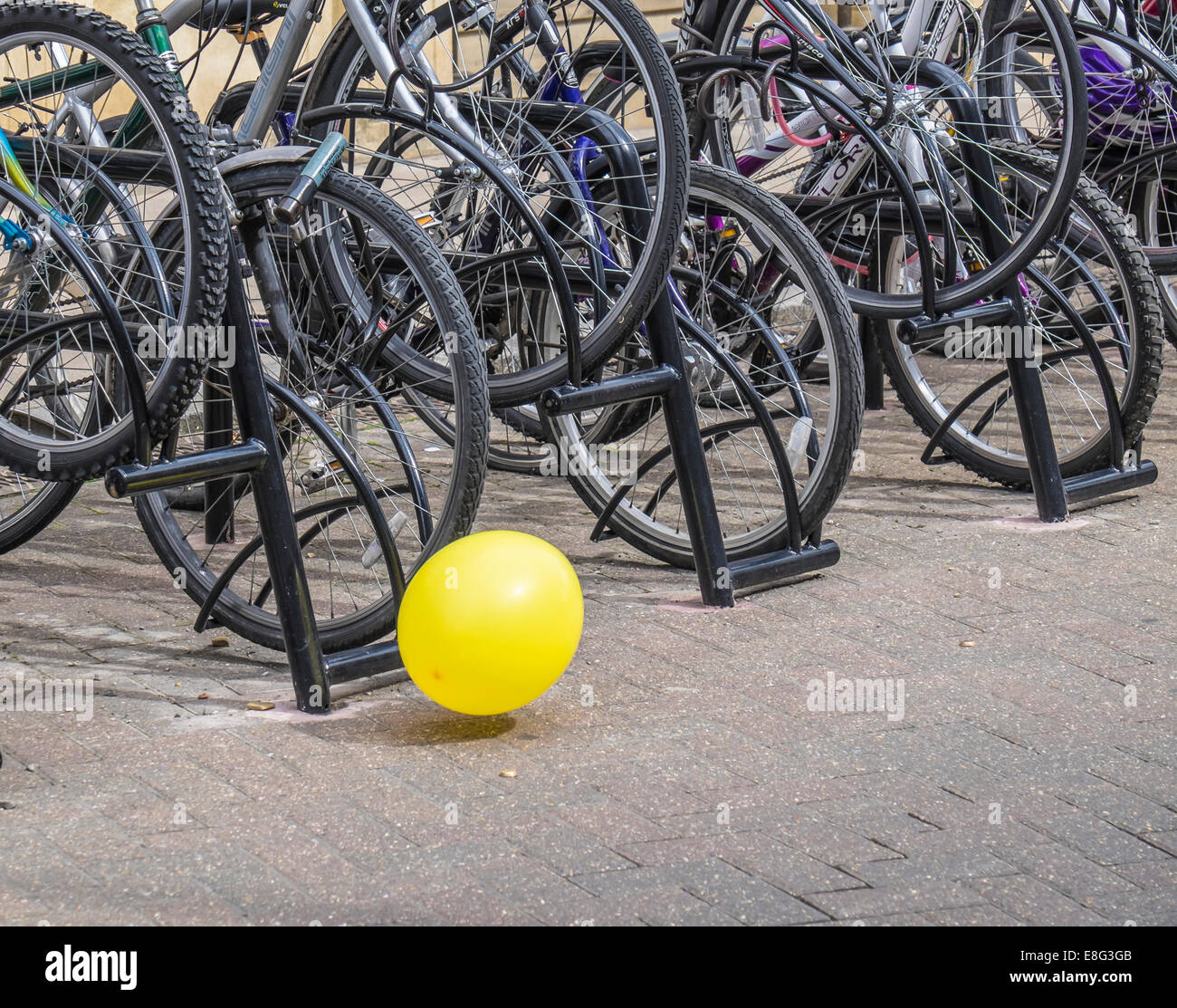 Palloncino giallo viene soffiato lungo il terreno di fronte a parcheggio biciclette Foto Stock