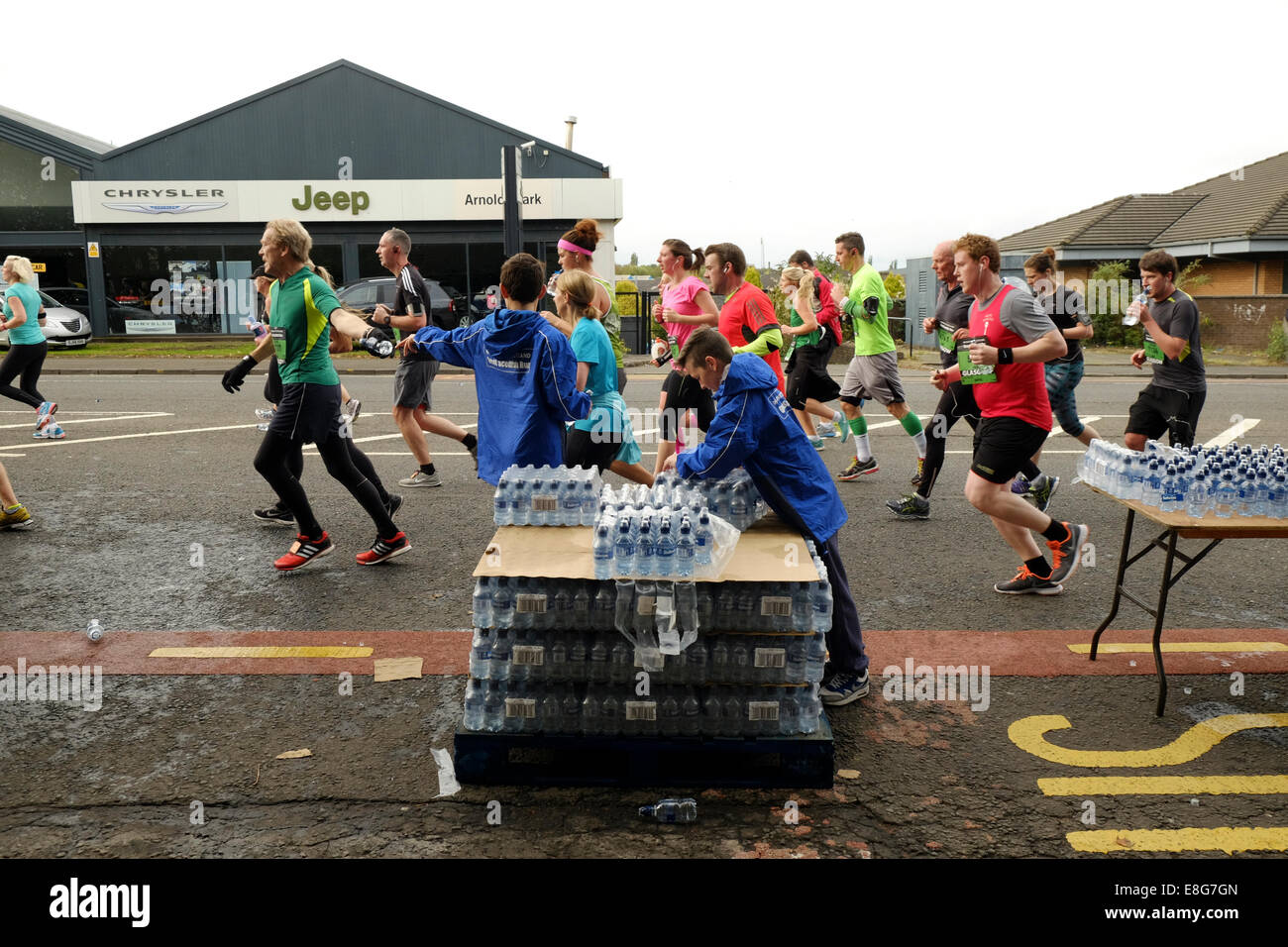 Giovani aiutanti di consegnare acqua per corridori della maratona durante la Grande esecuzione scozzese di Glasgow il 5 di ottobre Foto Stock