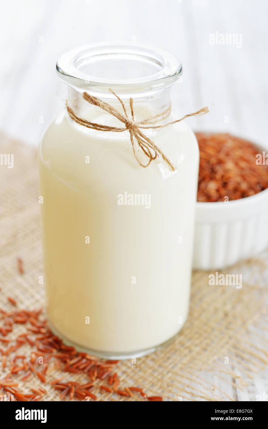 Riso Latte in bottiglia bianca su sfondo di legno. Vegani e vegetariani concetto di latte. Foto Stock