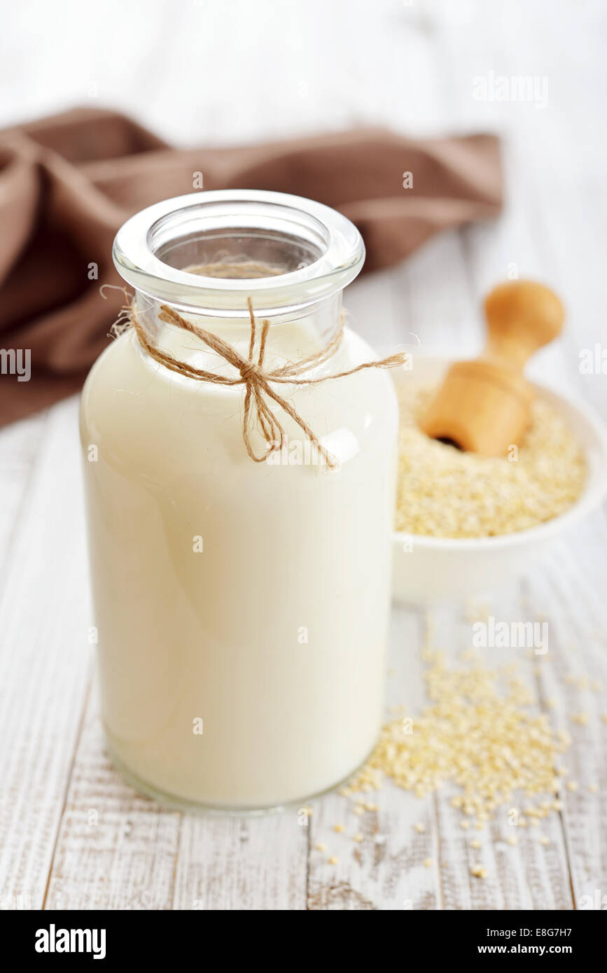 La quinoa latte in bottiglia di vetro su sfondo di legno Foto Stock
