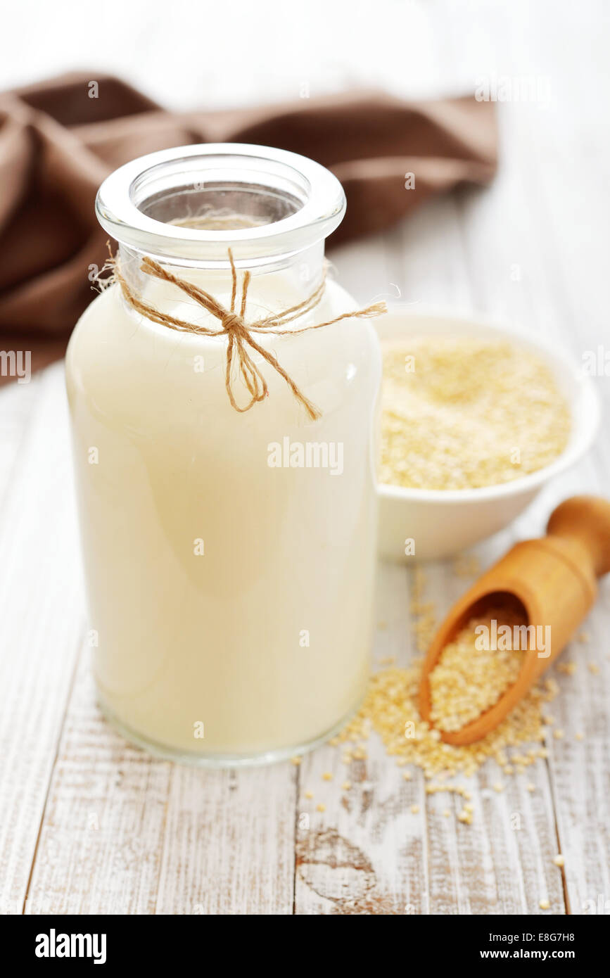 La quinoa latte in bottiglia di vetro su sfondo di legno Foto Stock