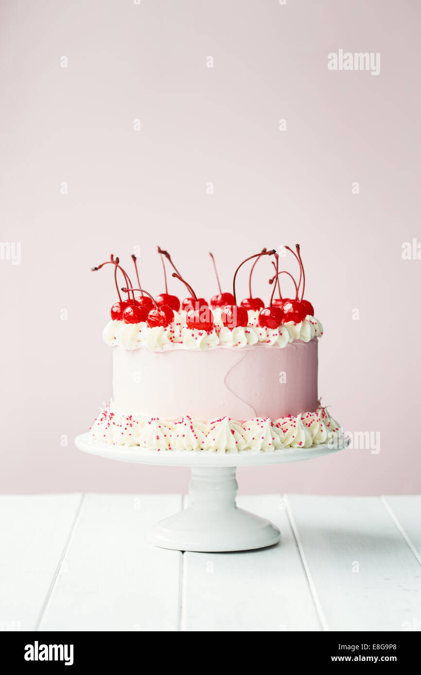 Torta decorata con la glassa e ciliegie al maraschino Foto Stock