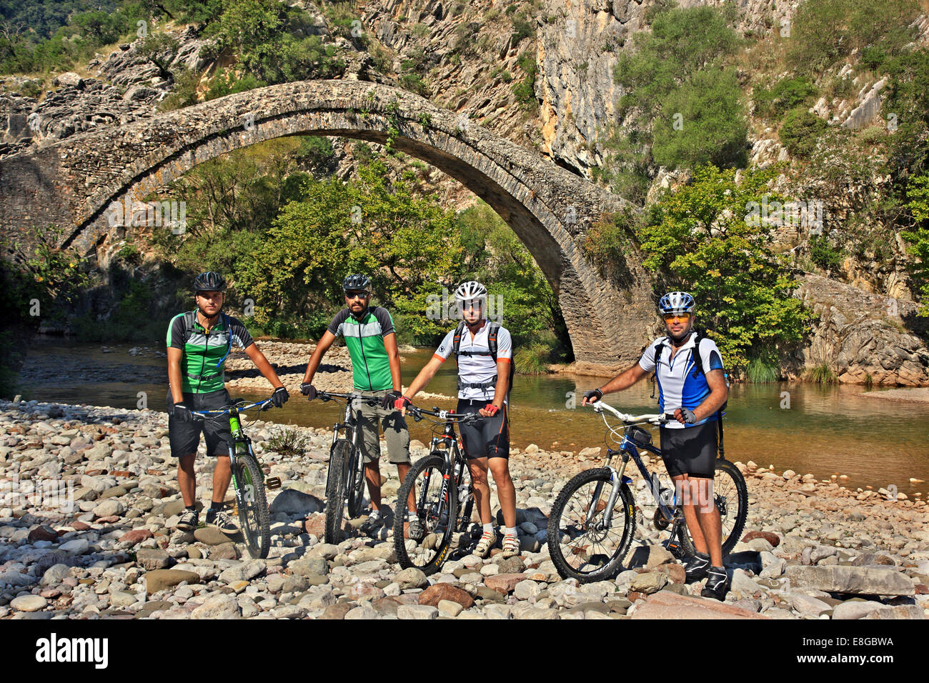 Gli amanti della mountain bike presso la pietra ponte arcuato di Artotiva (noto anche come "Kamara') e il fiume Evinos, Aitoloakarnania, Grecia Foto Stock
