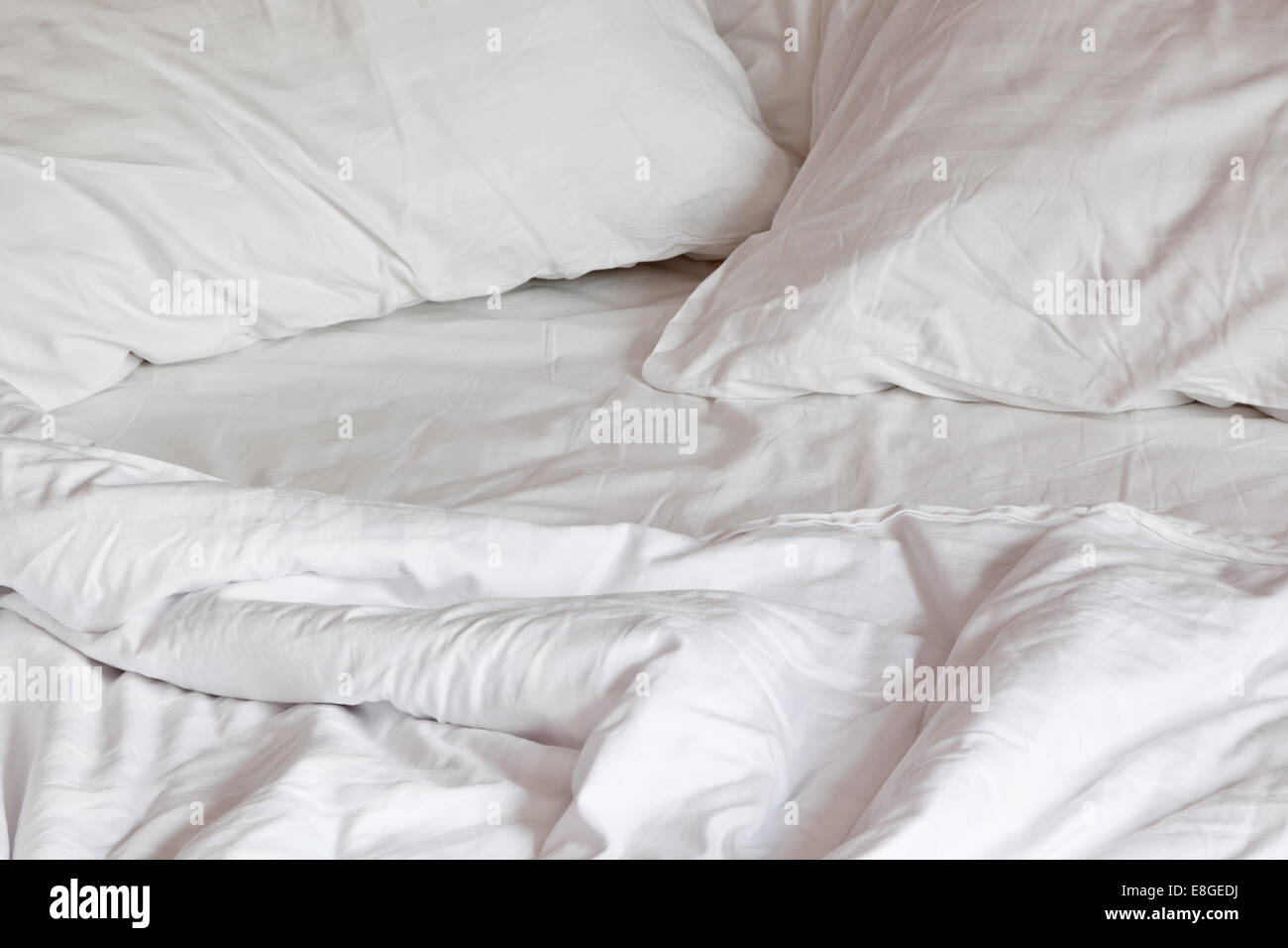 Confortevole letto disordinato con cuscini e piumino Foto Stock