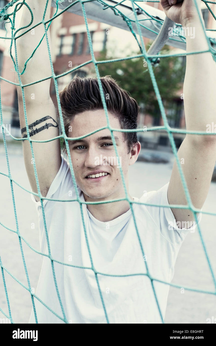 Ritratto di sorridere studente di scuola superiore dietro soccer net Foto Stock