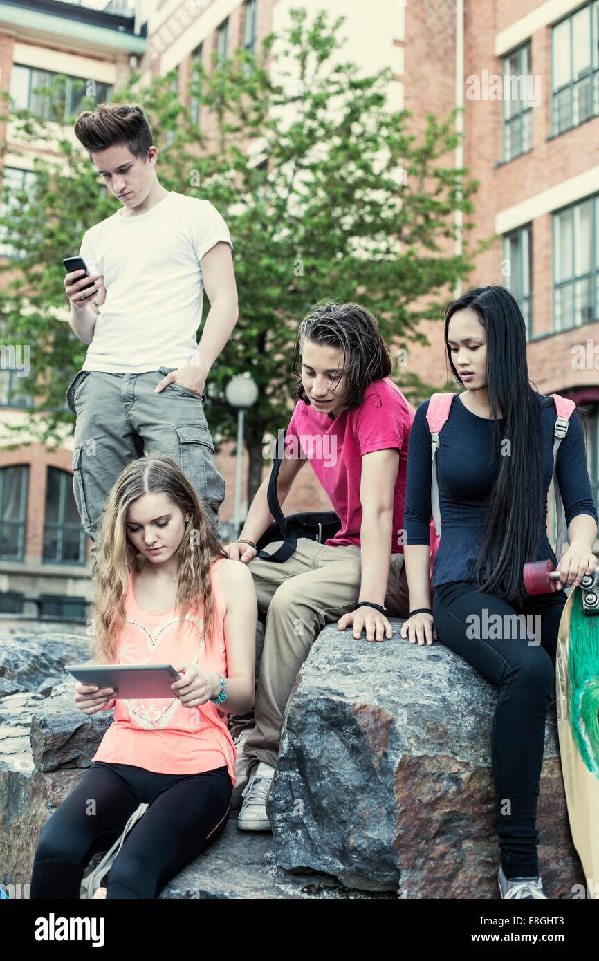 Gli studenti delle scuole superiori utilizzando tecnologie a schoolyard Foto Stock