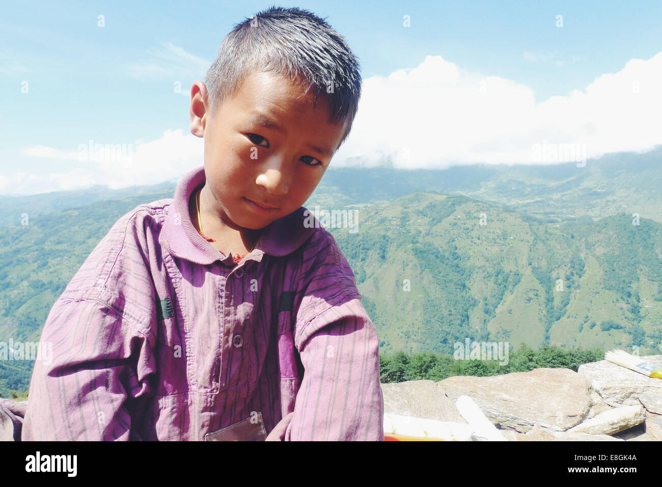 Ritratto di un ragazzo nepalese seduto su un muro, Nepal Foto Stock