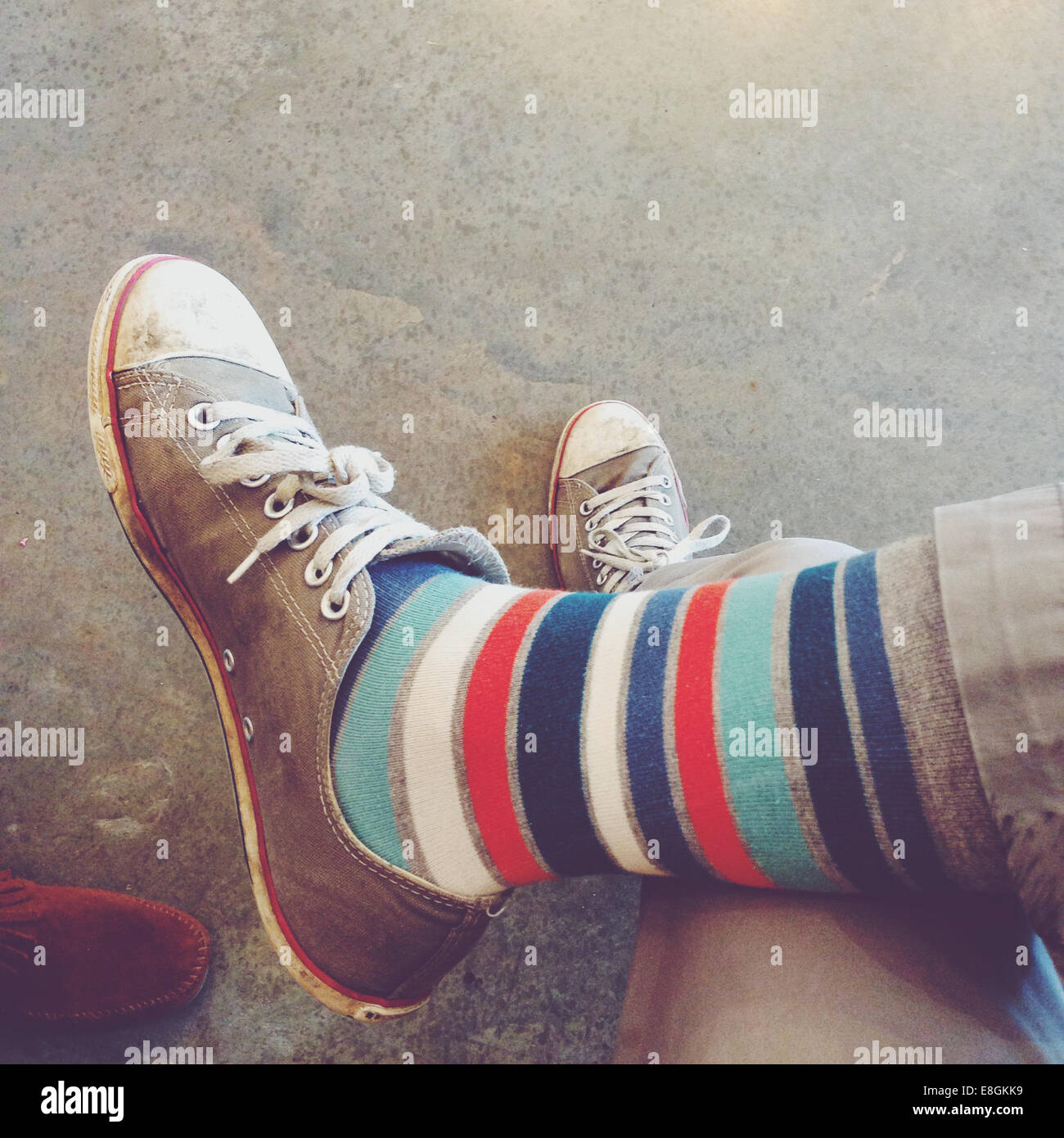 Primo piano di una persona che indossa calzini a righe e scarpe da ginnastica Foto Stock