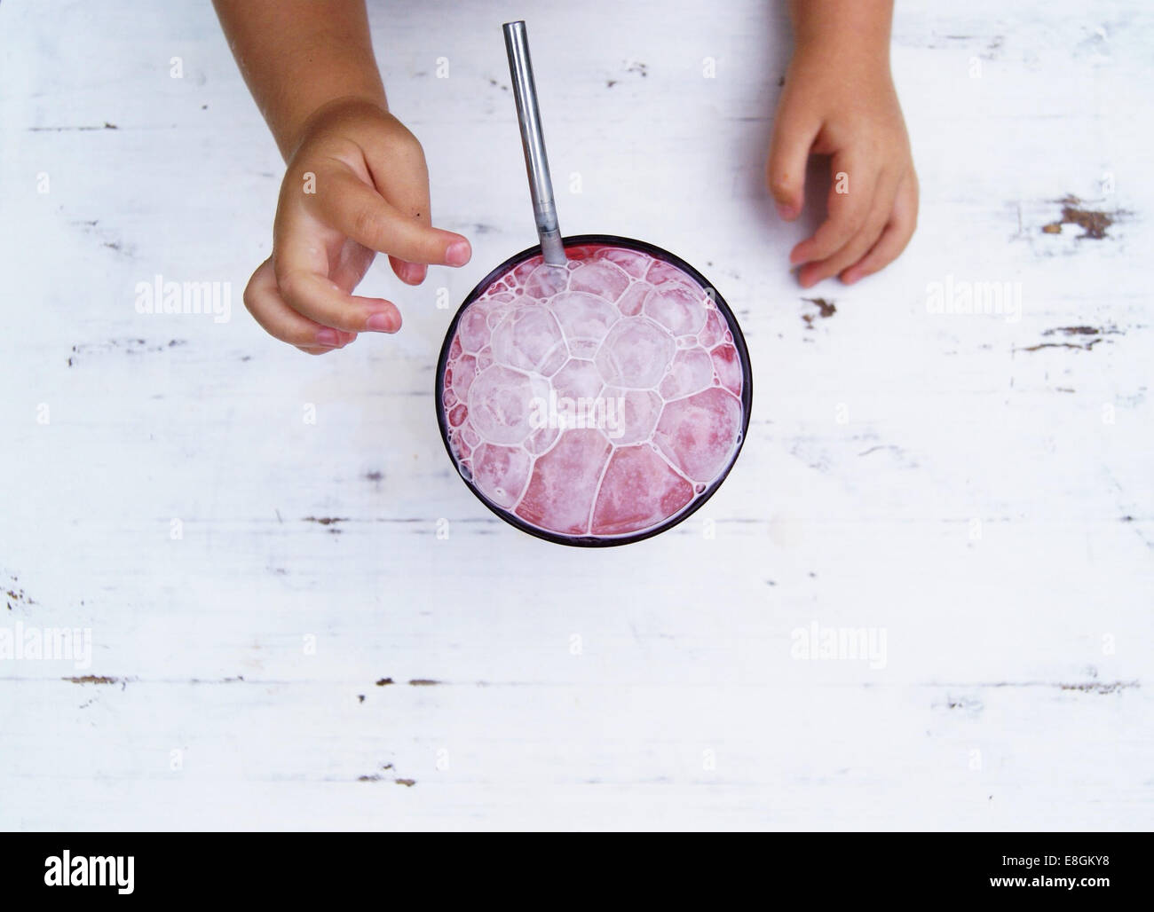 Bambino con le mani in mano per raggiungere un frullato fragole con bolle Foto Stock Bambino con le mani in mano per raggiungere un frullato fragole con bolle Foto Stock