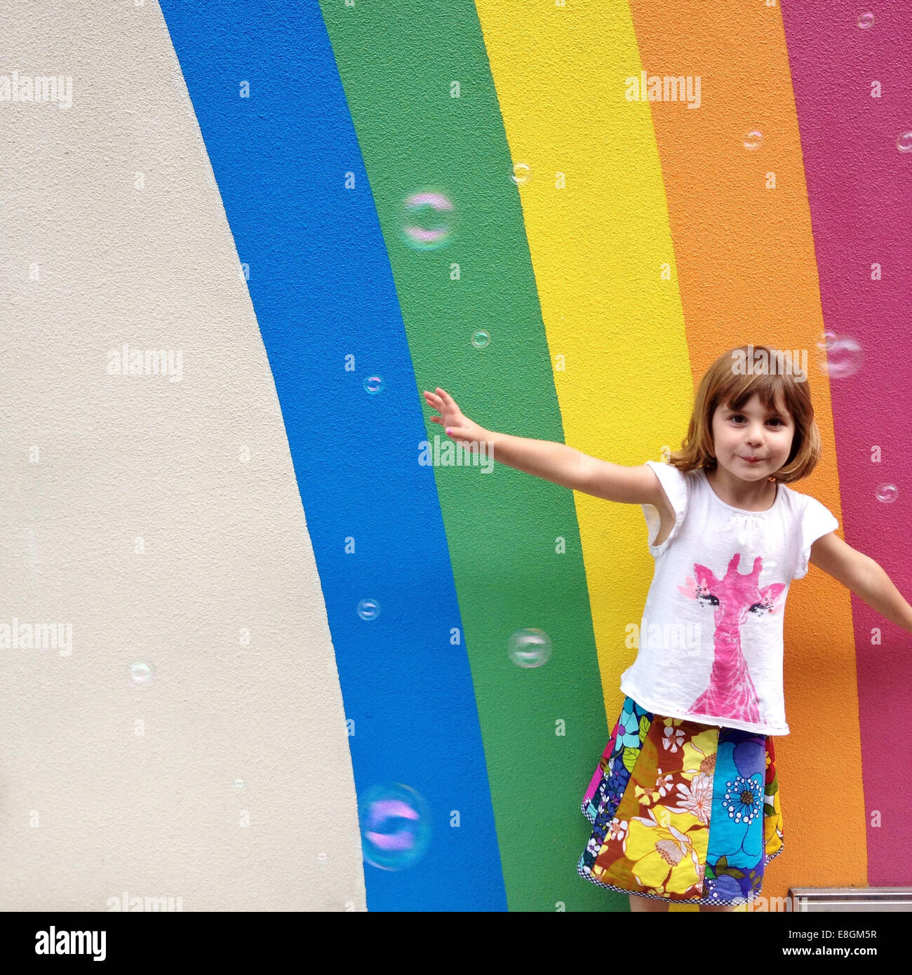 La ragazza (4-5) ballando con bolla di fronte dipinto di Rainbow Foto Stock