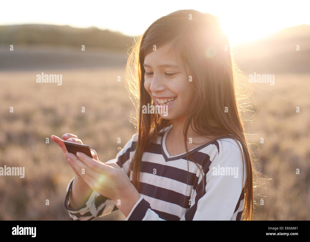 Ragazza sorridente in piedi di Prato per la messaggistica di testo Foto Stock