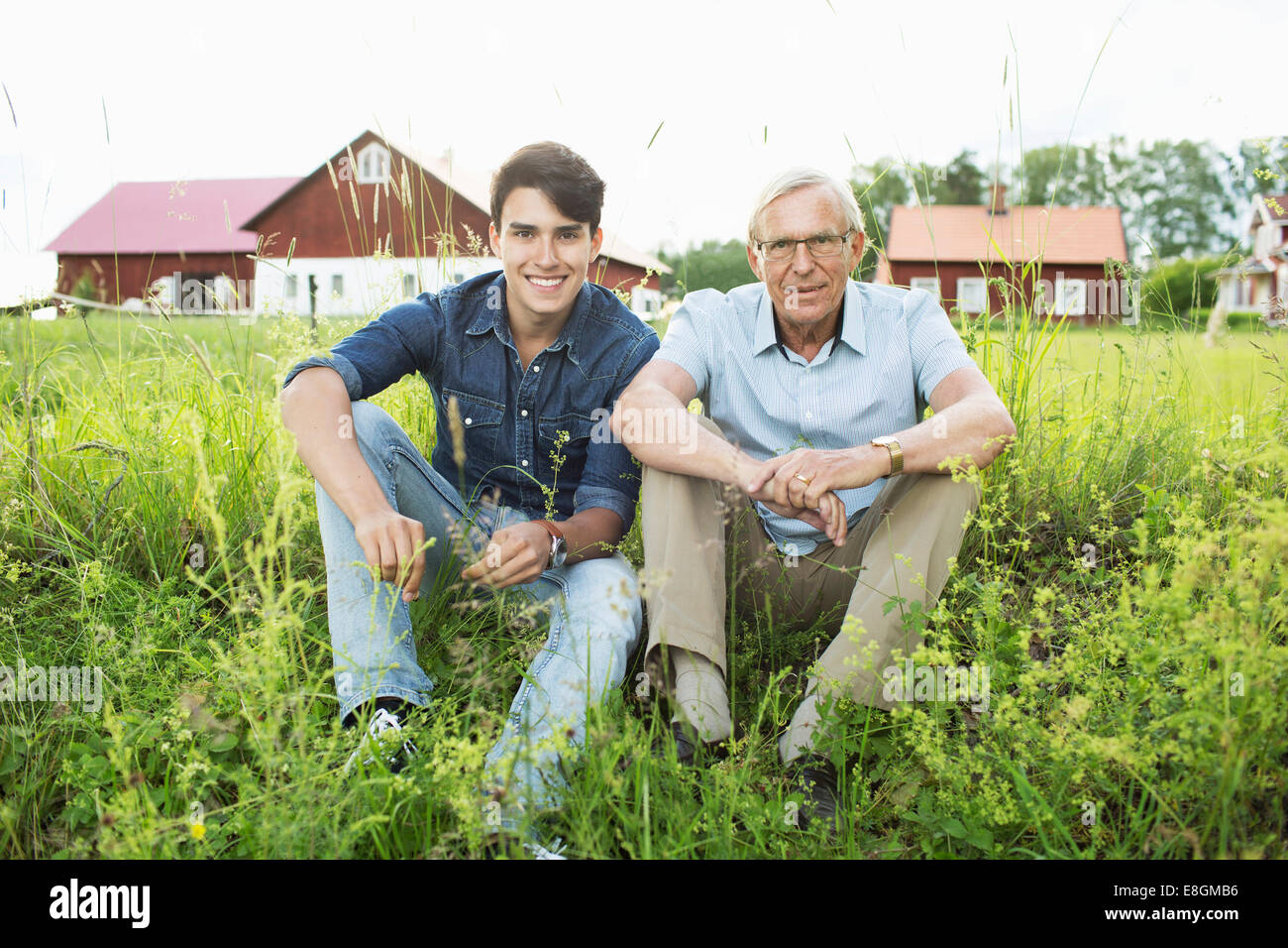 A piena lunghezza ritratto del nonno e nipote seduta sul campo erboso Foto Stock