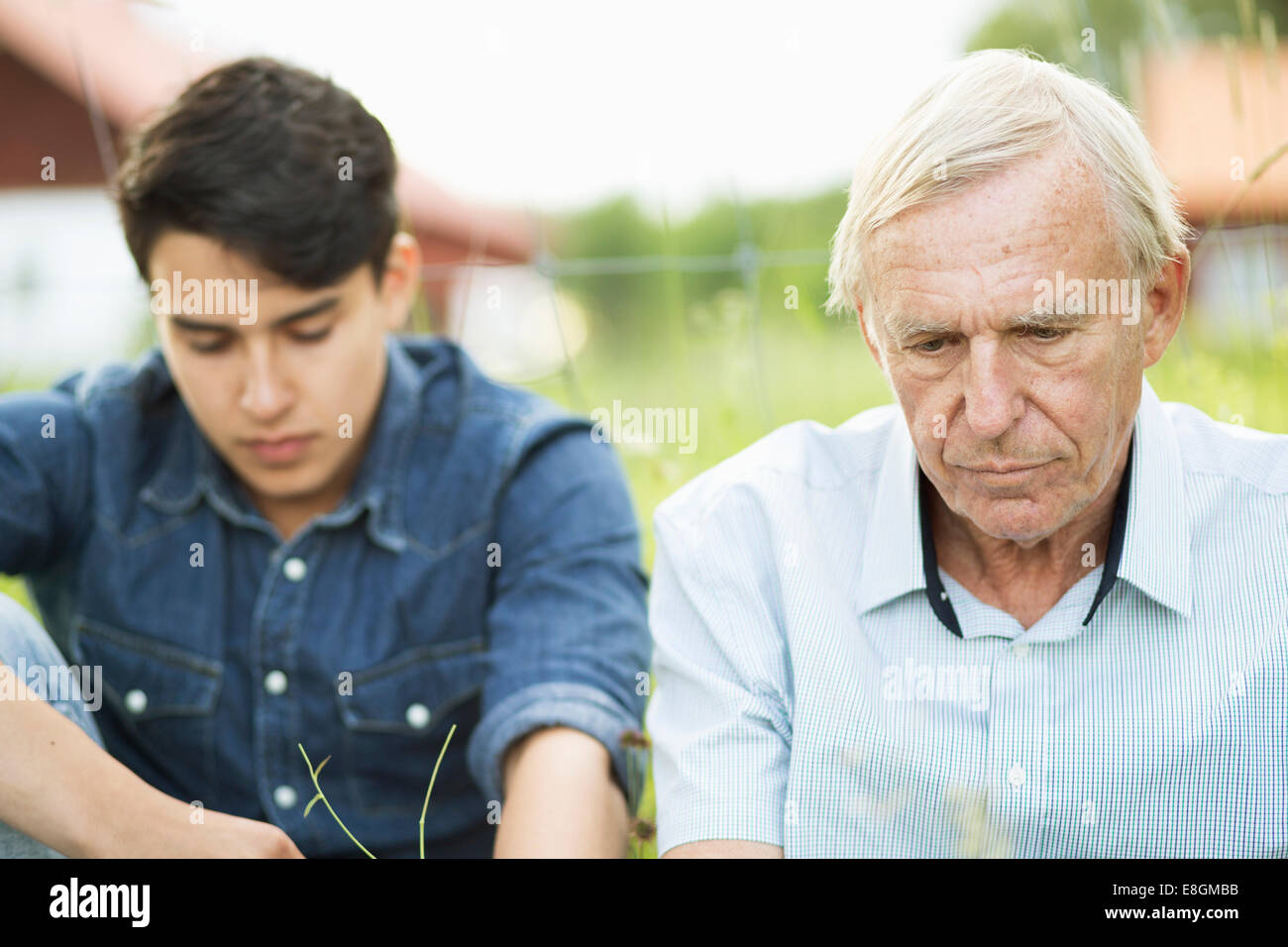 Riflessivo uomo senior con il nipote seduto in cantiere Foto Stock