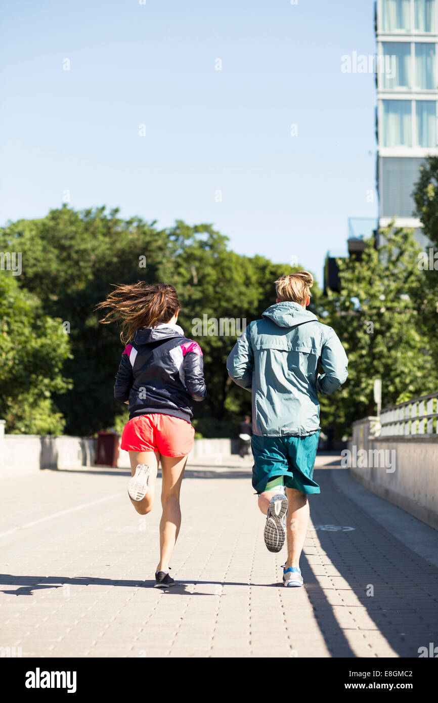 Lunghezza piena vista posteriore del multi-etnico giovane jogging sul ponte Foto Stock