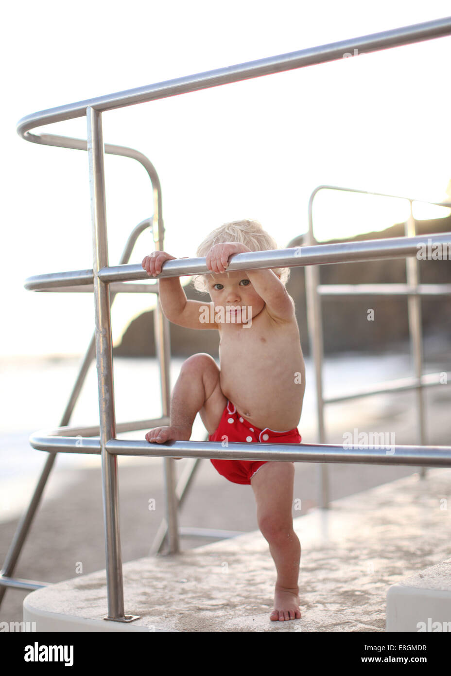 Il Toddler arrampicata sulla torre bagnino ringhiere Foto Stock
