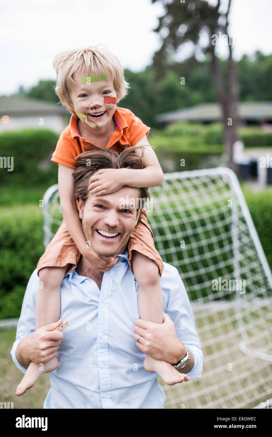 Ritratto di Padre felice che trasportano ragazzo ferito sulle spalle Foto Stock