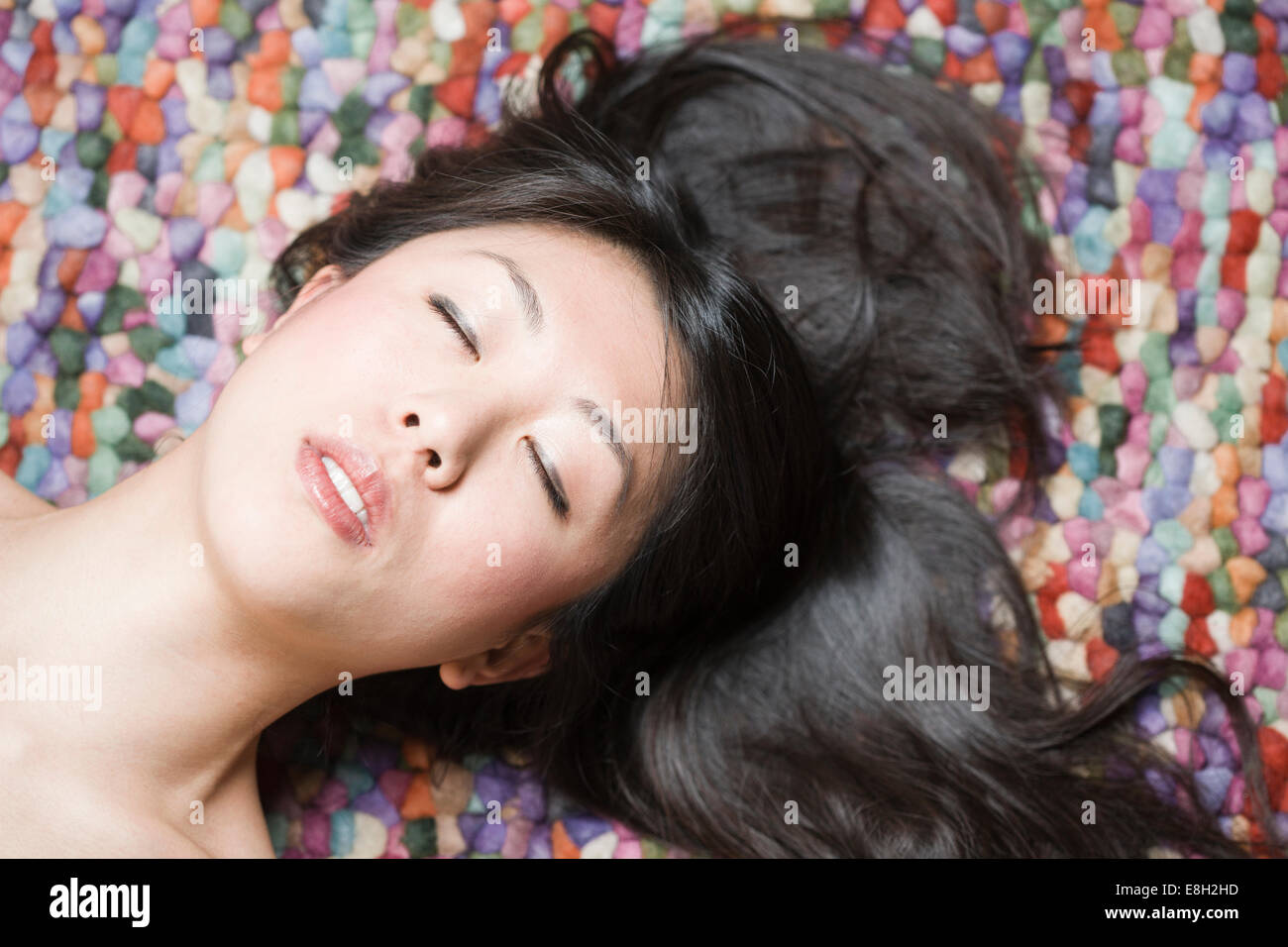 Ritratto di donna asiatica con gli occhi chiusi di fronte a terra colorata Foto Stock