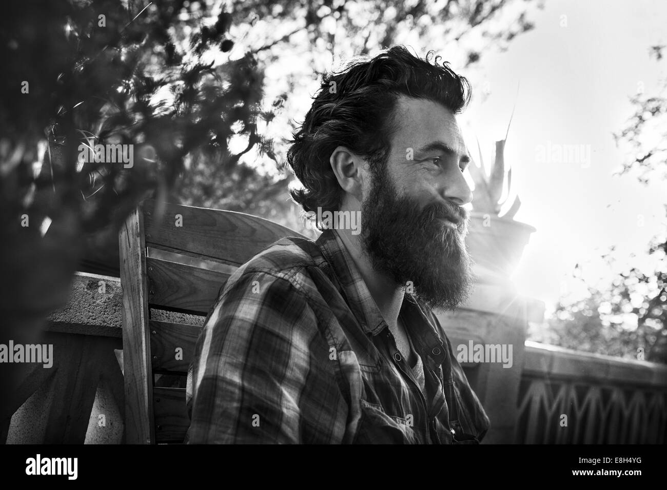 Uomo sorridente con barba folta sul portico Foto Stock