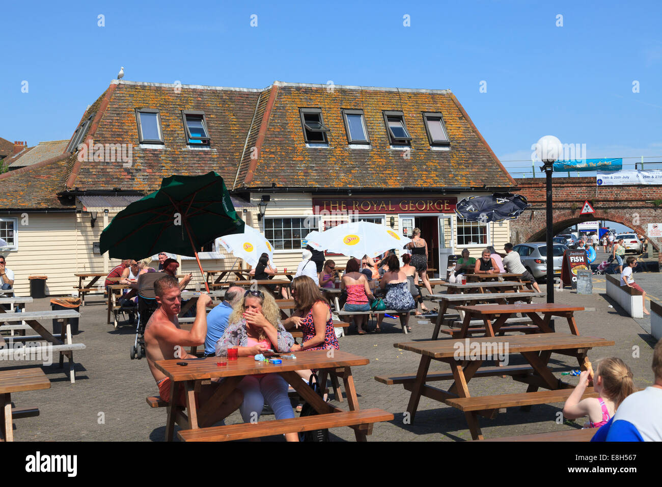 Le persone che si godono il sole estivo al di fuori del Royal George Pub vicino al porto a Folkestone. Foto Stock