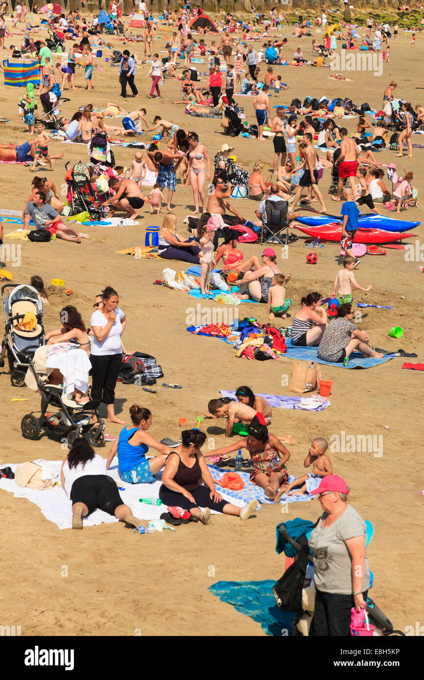 Le persone che si godono il sole su una spiaggia affollata a Folkestone. Foto Stock