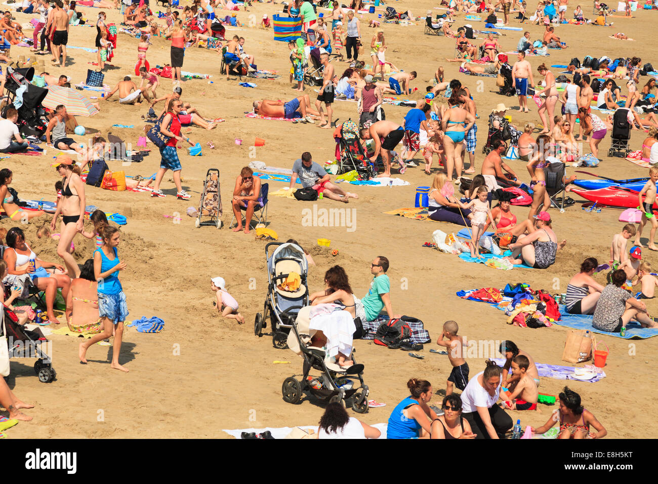 Le persone che si godono il sole su una spiaggia affollata a Folkestone. Foto Stock