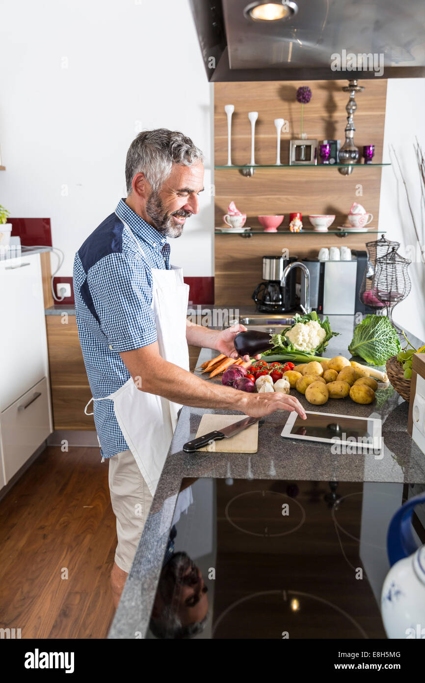 L'Austria, l'uomo in cucina con tavoletta digitale la preparazione di alimenti Foto Stock