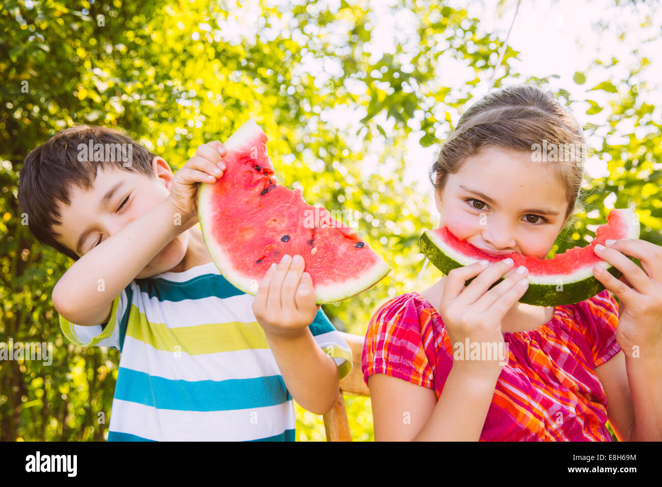 I bambini a mangiare fette di cocomero in giardino Foto Stock