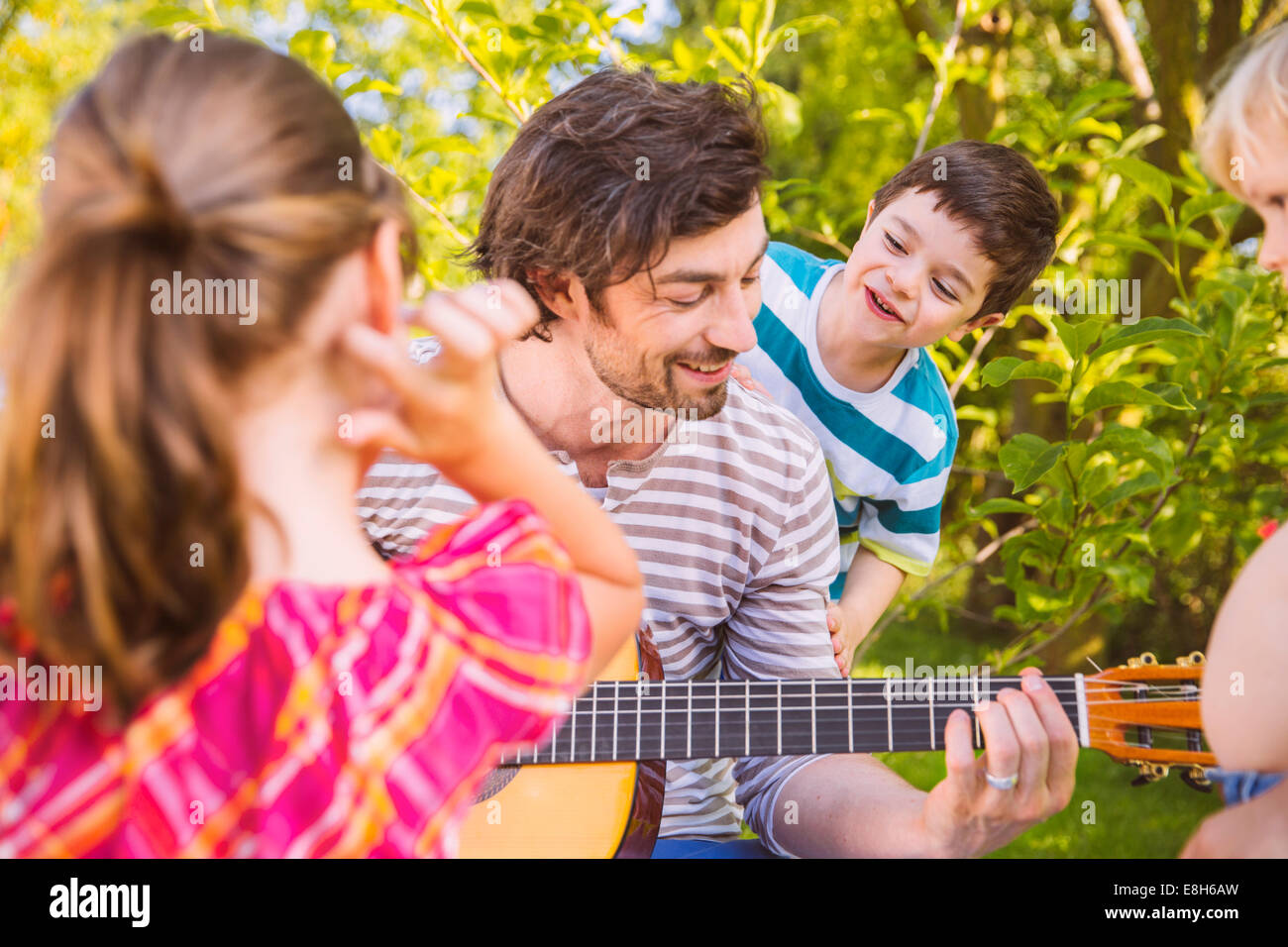 Padre con i bambini a suonare la chitarra in giardino Foto Stock