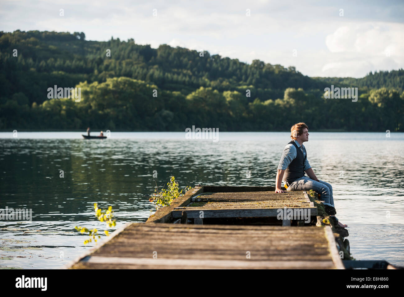 In Germania, in Renania Palatinato, Laach Lago, uomo seduto sulla passerella in legno Foto Stock