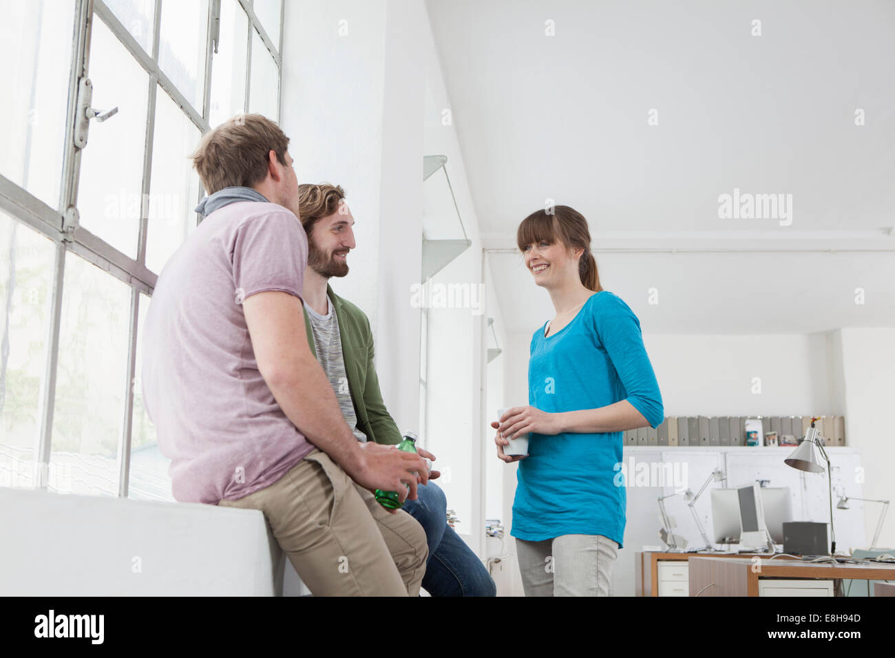 Tre colleghi per comunicare in un ufficio creativo Foto Stock