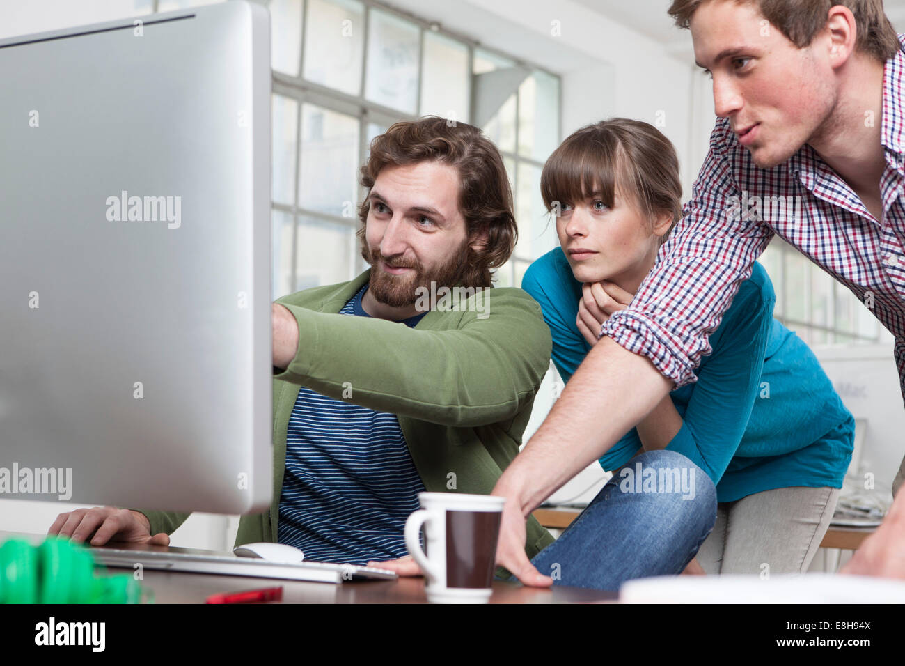 Tre colleghi guardare il computer in un ufficio creativo Foto Stock