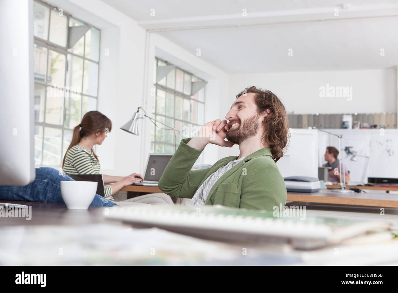 Giovane uomo telefonando alla sua scrivania in un ufficio creativo Foto Stock
