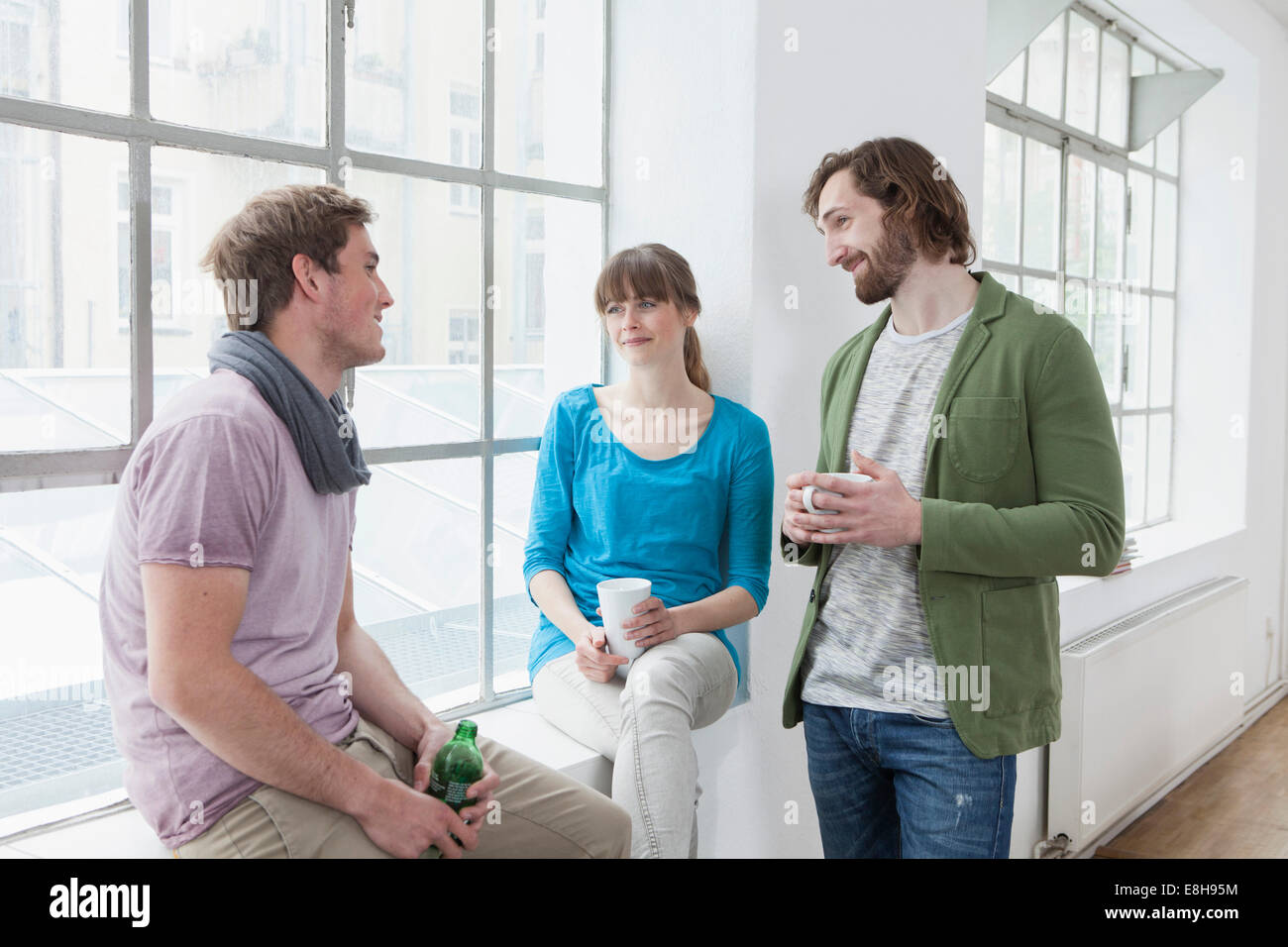 Tre colleghi per comunicare in un ufficio creativo Foto Stock