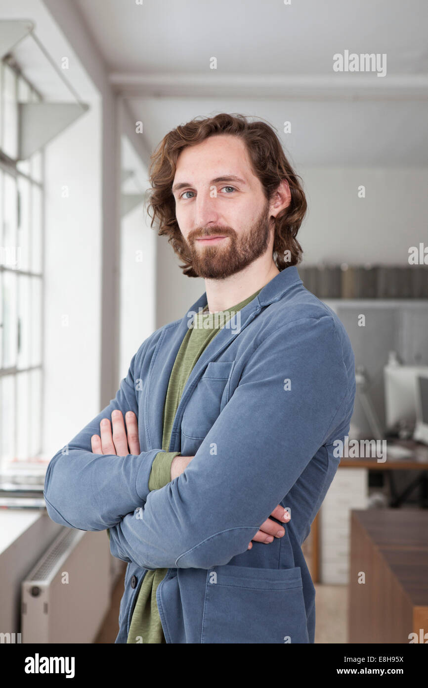 Ritratto di un uomo con le braccia conserte in un ufficio creativo Foto Stock