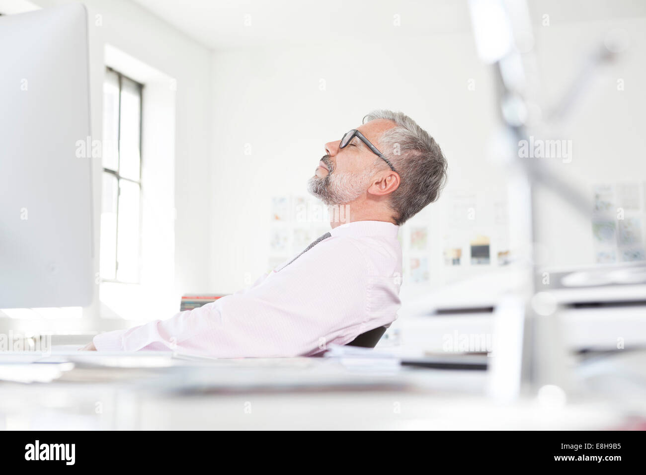 Uomo al lavoro in un momento di relax a sua scrivania in un ufficio Foto Stock
