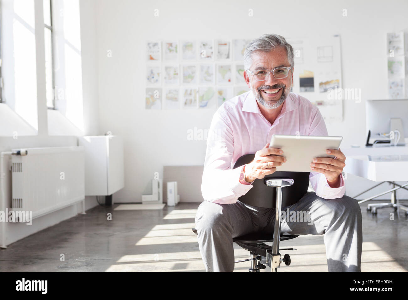 Ritratto di imprenditore sorridente con tavoletta digitale in un ufficio Foto Stock