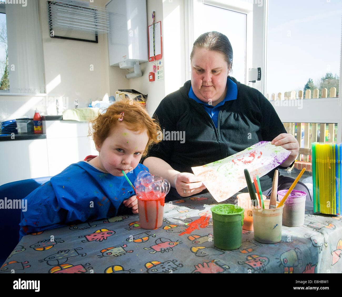 Bambino in pre-scuola di classe con Learning Support Assistant (LSA), Oxfordshire,UK pittura con bolle Foto Stock