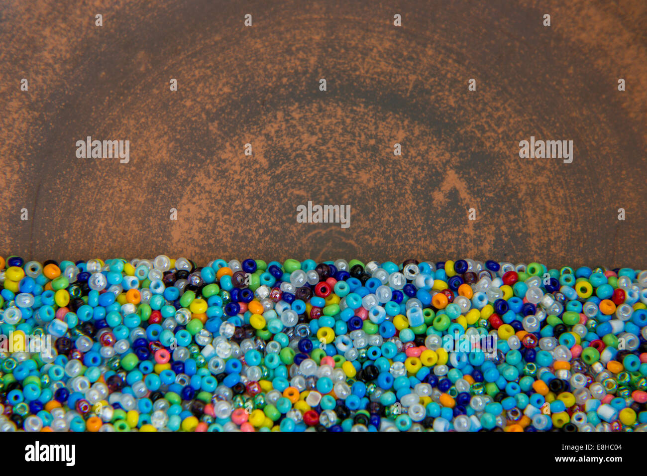 La dispersione di molte piccole, multicolore perle perle su sfondo di argilla Foto Stock