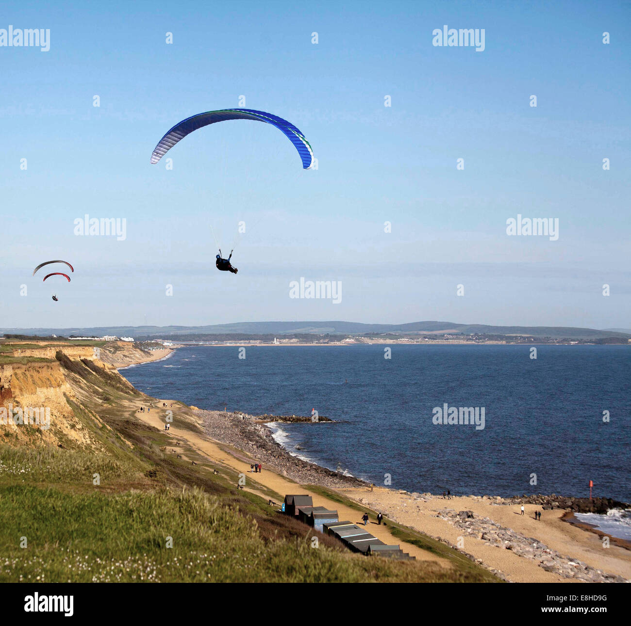 Parapendio volare sopra le scogliere di Barton on Sea Hampshire in una bella giornata d'estate con l'Isola di Wight in background Foto Stock