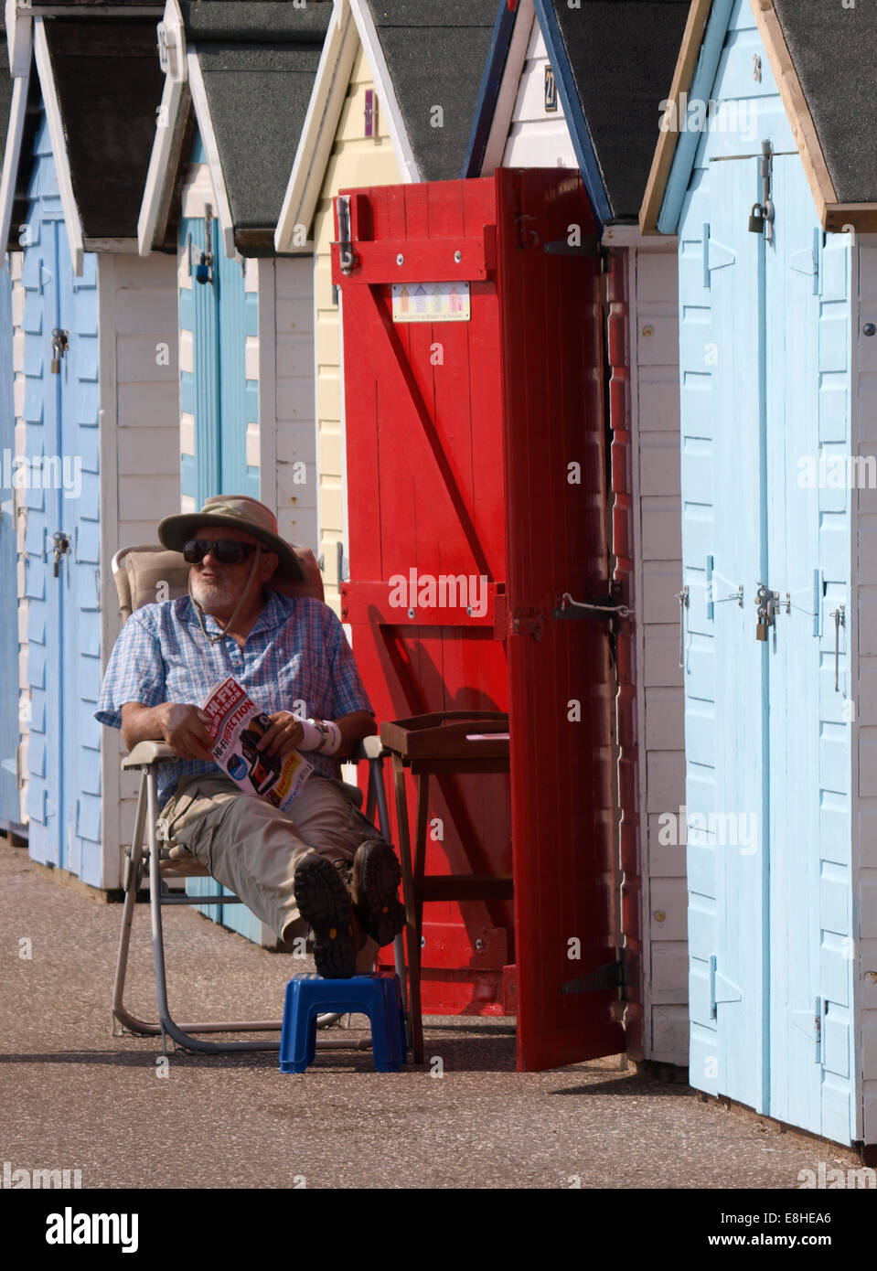 Il vecchio uomo seduto fuori Beach Hut, Seaton, Devon, Regno Unito Foto Stock