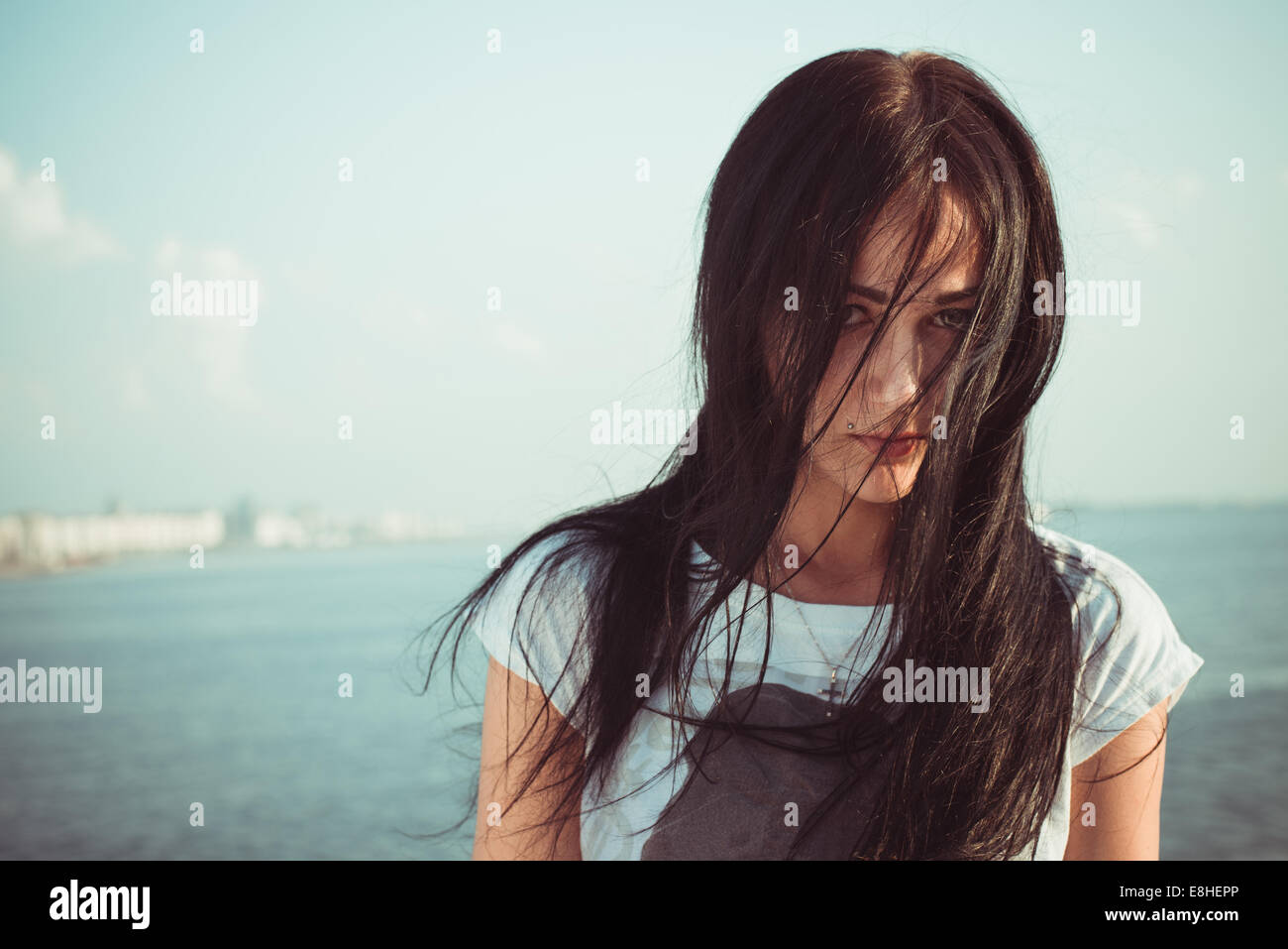 Ritratto outdoor giovane donna sulla spiaggia con pasticcio lunghi capelli neri Foto Stock