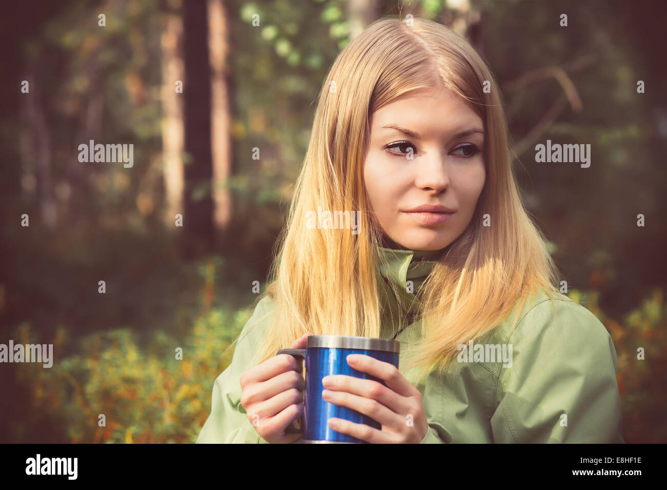 Giovane donna con metallo touristic tazza da tè Outdoor Lifestyle e concetto di escursionismo con foresta sullo sfondo Foto Stock