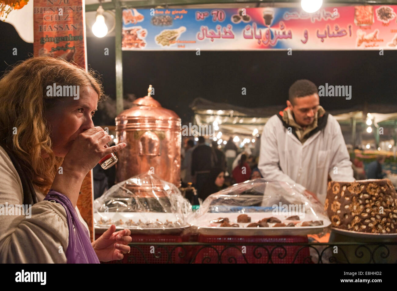 Ritratto orizzontale di un turista di bere il tè alla menta in una fase di stallo in Piazza Jemaa el Fna (Djemaa El Fnaa) in Marrakech di notte Foto Stock