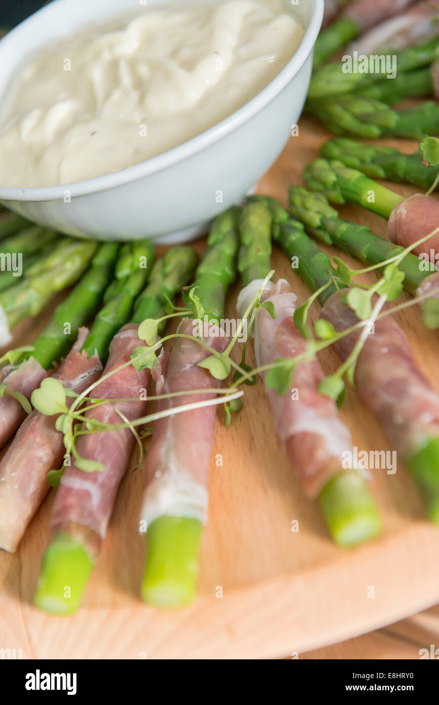 Gli asparagi avvolti nel prosciutto con dip, saporite tartine su un vassoio. Foto Stock