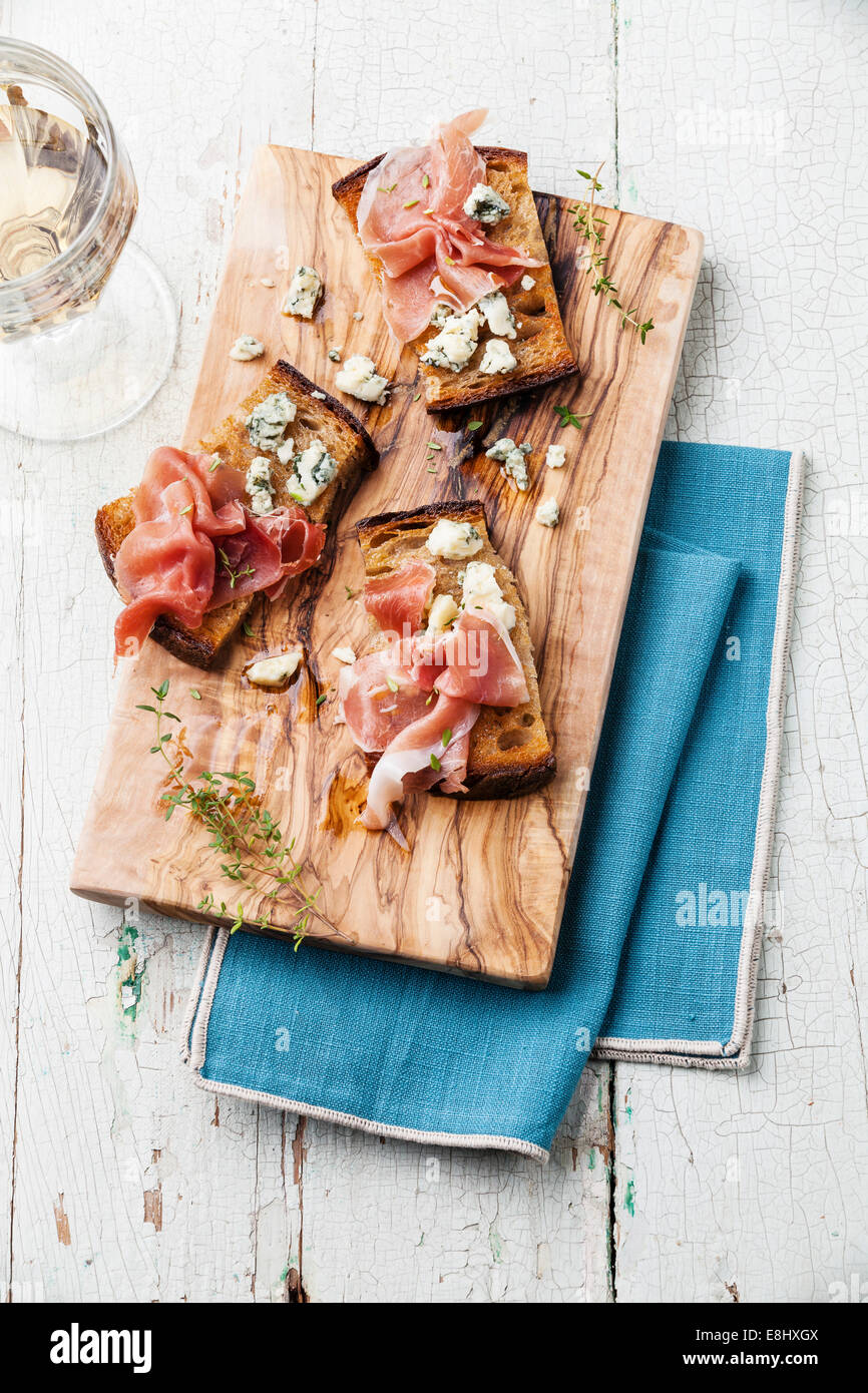 Bruschette con Blue di prosciutto e formaggio alla griglia su pane croccante blu su sfondo di legno Foto Stock